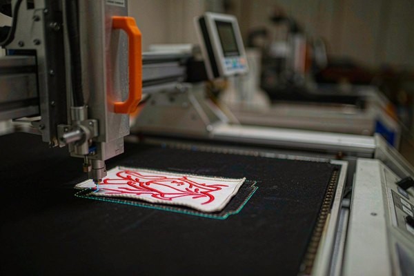 Laser cutting machine tracing the outline of a custom shaped patch with a visible sealed edge