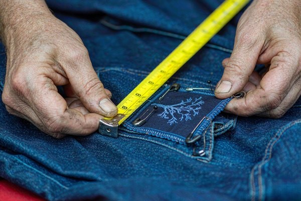 Measuring denim jacket patch placement on the left chest with tailor's tape for correct positioning