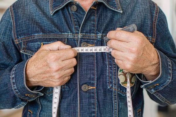 Patch placement guide: tailor measuring custom patch positioning on a denim jacket chest with tailor's tape