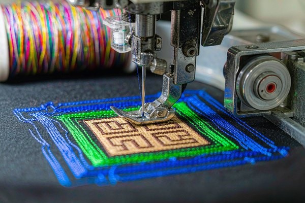 Embroidered patch thread types: rayon, polyester, and metallic thread spools in multiple colors beside custom patches