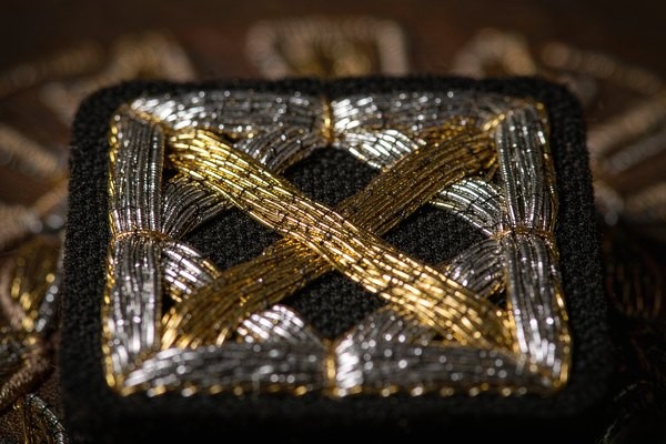 Metallic embroidery thread close-up showing reflective gold and silver filament stitched on a custom patch